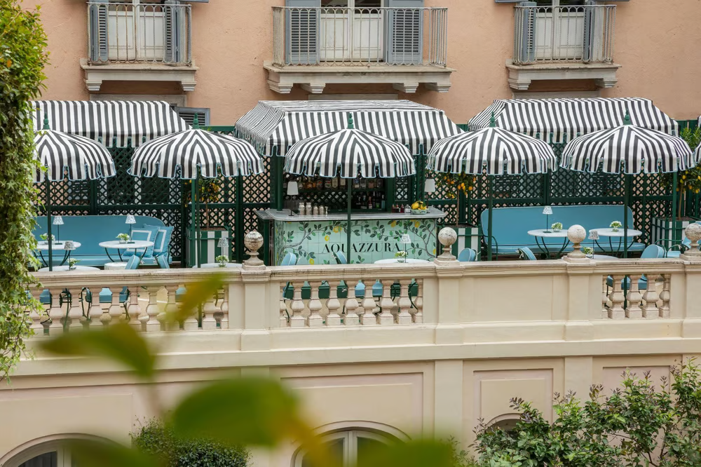 Hotel de Russie 酒店的 Aquazzura 酒吧露台设有标志性的条纹檐篷，将俏皮的魅力与罗马的优雅融为一体。